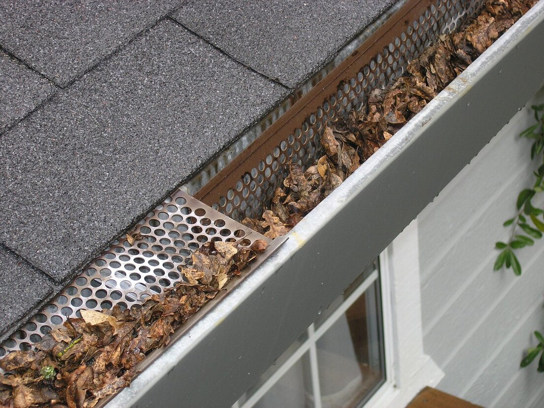 Removing leaves from a gutter with a scoop